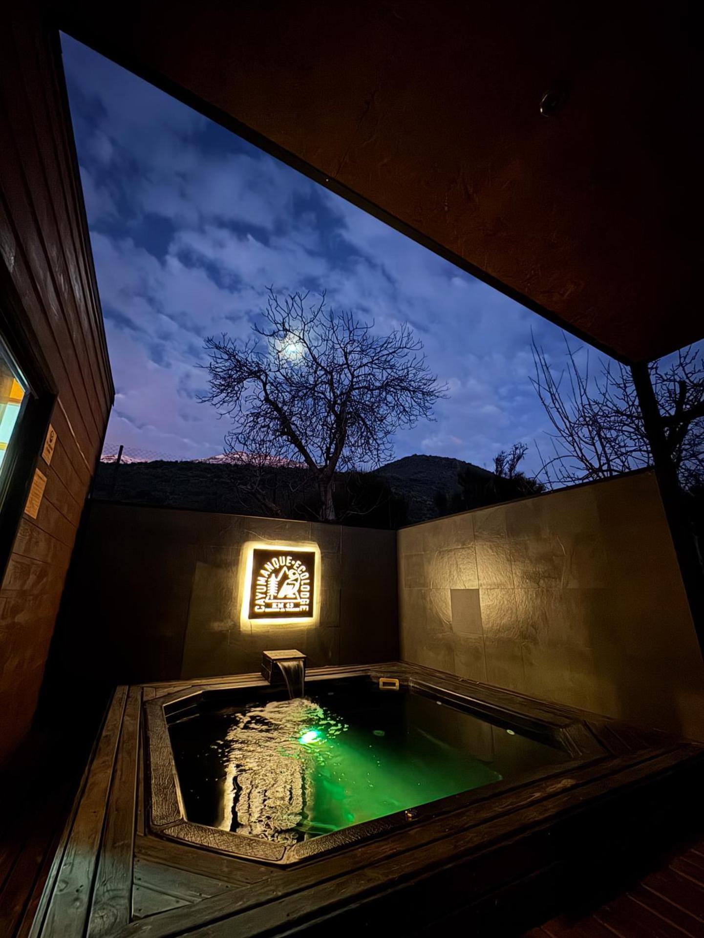 Piscina-jacuzzi iluminada al anochecer en Cayumanque Ecolodge